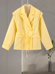 Yellow jacket hanging on a gray wall with a plant in the background