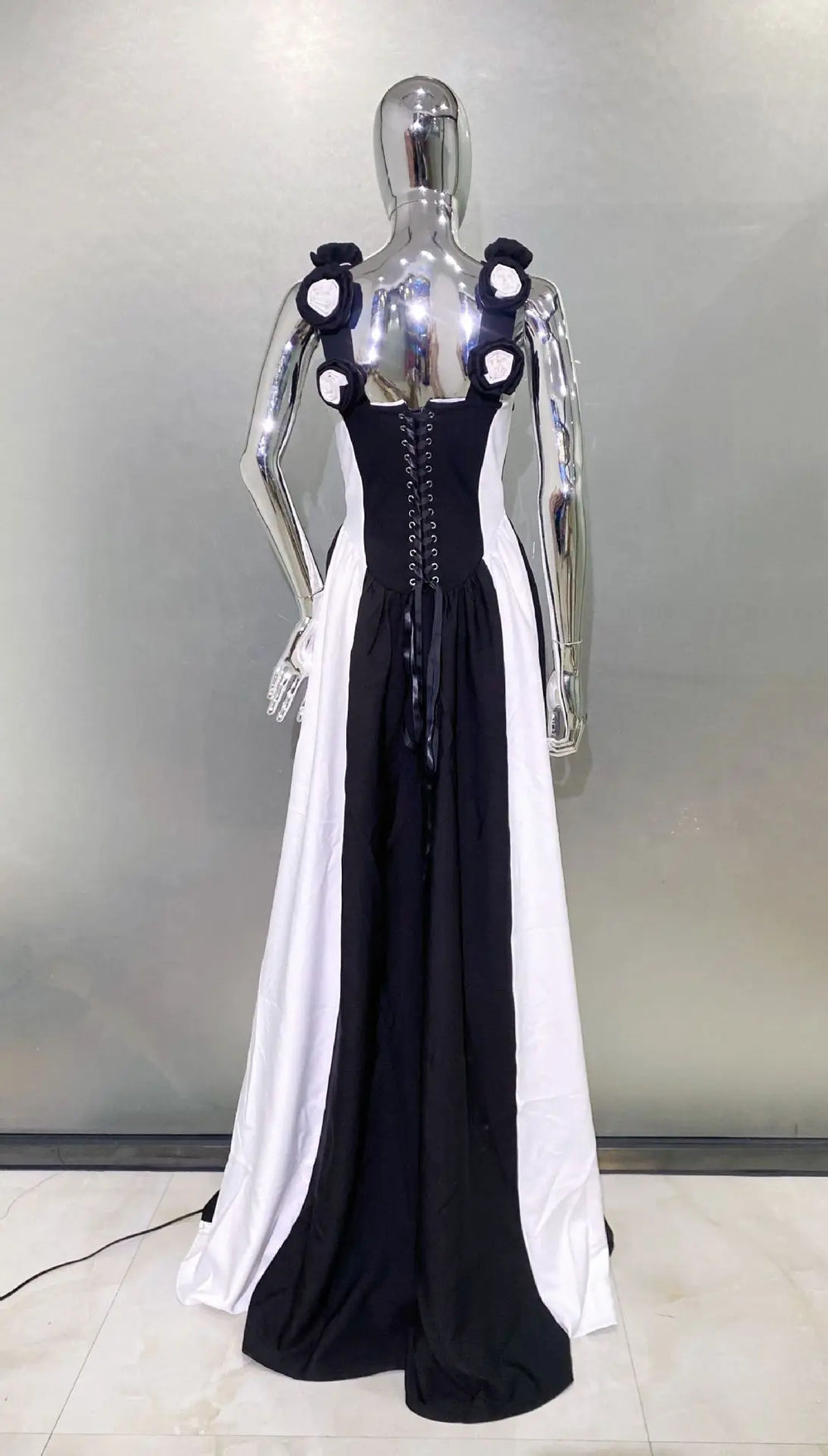 Mannequin wearing a black and white dress with floral details on a neutral background