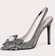 High-heeled shoe with decorative bow and pearl on a light pink background