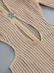 Close-up of a beige knit garment with a brooch on a gray background