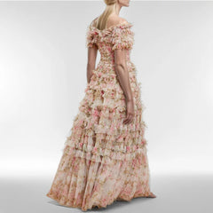 Woman wearing a floral off-shoulder gown on a plain background