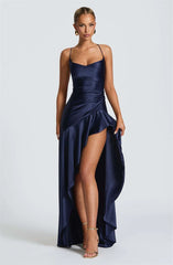 Woman wearing a navy blue evening gown with a slit on a white background