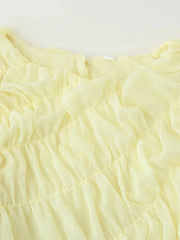 Close-up of light yellow fabric with ruffled texture on a white background