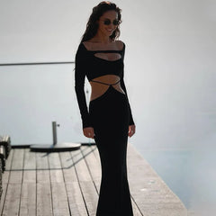 Woman in a black dress standing on a dock with water in the background