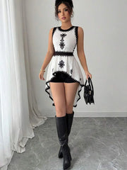 Woman wearing a black and white dress with knee-high boots in a room.