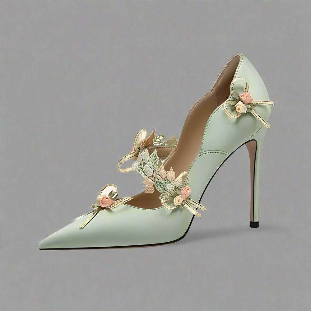Green high-heeled shoe with floral decorations on a white background