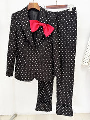 Black polka dot print blazer and trousers with a red bow detail on a hanger.