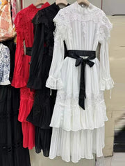 White lace dress with a black belt on a rack with other dresses.