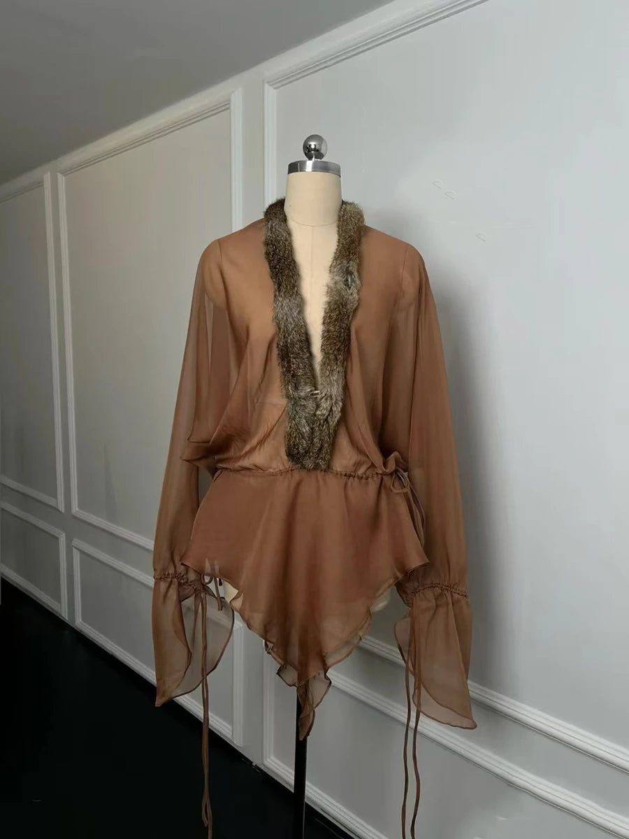 Brown sheer top with fur collar on a mannequin against a white wall.