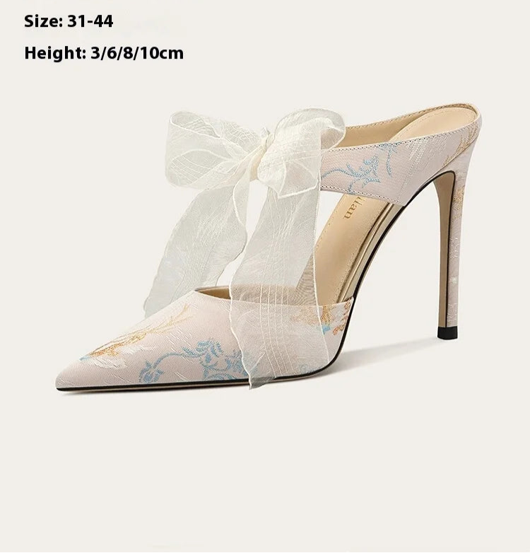 White high-heeled shoes with a bow on a white background