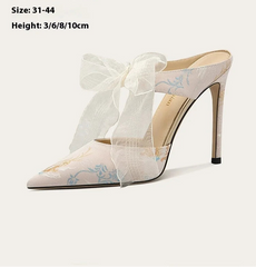 White high-heeled shoes with a bow on a white background