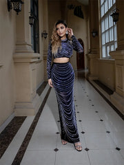 Woman in a sparkling two-piece outfit standing in an elegant hallway.