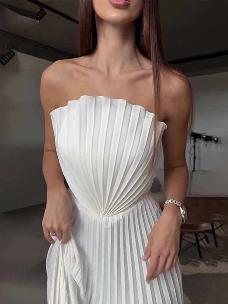 Woman wearing a white pleated strapless dress indoors.