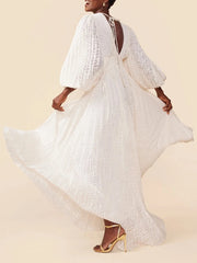 Woman wearing a white lace dress with long sleeves on a beige background