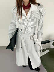 Person wearing a white pinstripe trench coat with a plain background