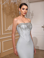 Woman wearing a strapless silver evening gown with a detailed bodice in an elegant room.