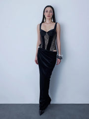 Woman wearing a black evening gown with lace detailing against a plain background