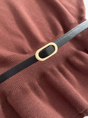 Close-up of a belt with a gold buckle on a brown fabric background