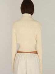 Person wearing a beige ribbed sweater and pants against a plain background