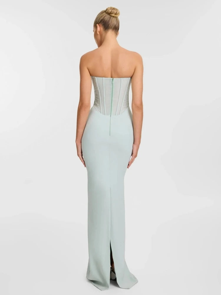 Woman wearing a strapless light blue gown with a high slit on a white background