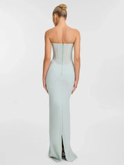 Woman wearing a strapless light blue gown with a high slit on a white background