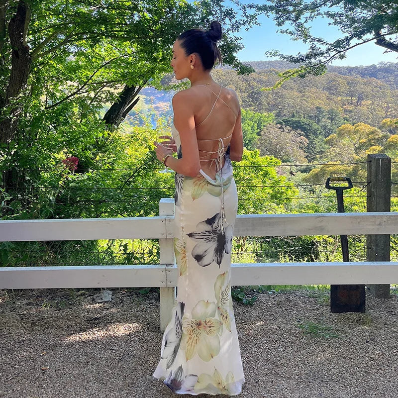 Woman in a floral dress standing outdoors with trees and mountains in the background