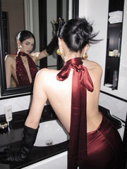 Woman in a red dress with a bow tie standing in front of a mirror.