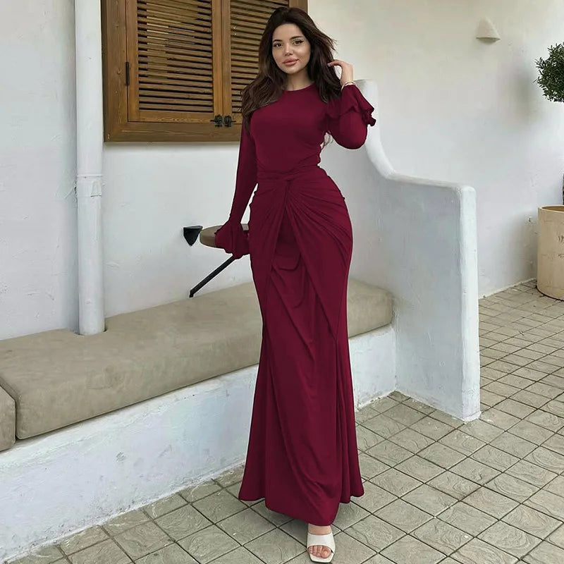 Woman in a burgundy dress standing in a room with white walls and tiled floor.