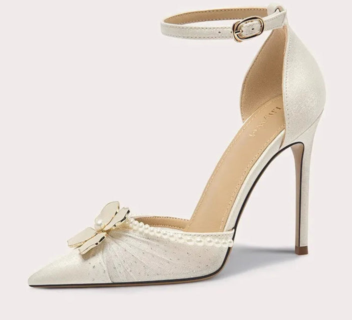 White high-heeled shoe with decorative bow on a light gray background