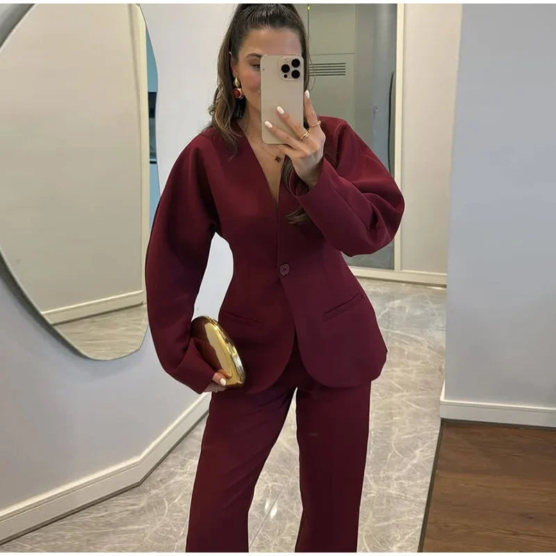 Person wearing a burgundy suit taking a mirror selfie.