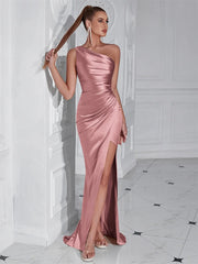 Woman wearing a pink one-shoulder dress with a slit in a white room.