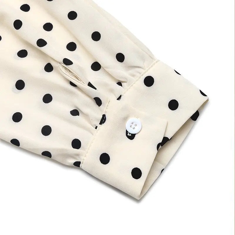Close-up of a beige fabric with black polka dots and a white button on a white background