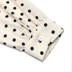 Close-up of a beige fabric with black polka dots and a white button on a white background