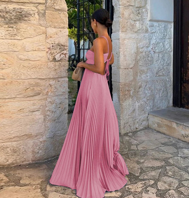 Woman in a pink dress standing in front of a stone wall.