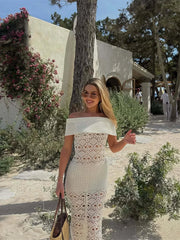 Woman in a white lace dress standing outdoors with a building and trees in the background