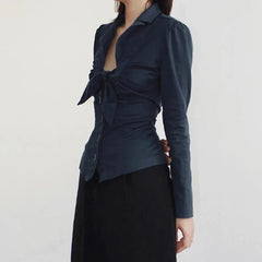 Navy blue top with a tie detail worn by a person on a white background