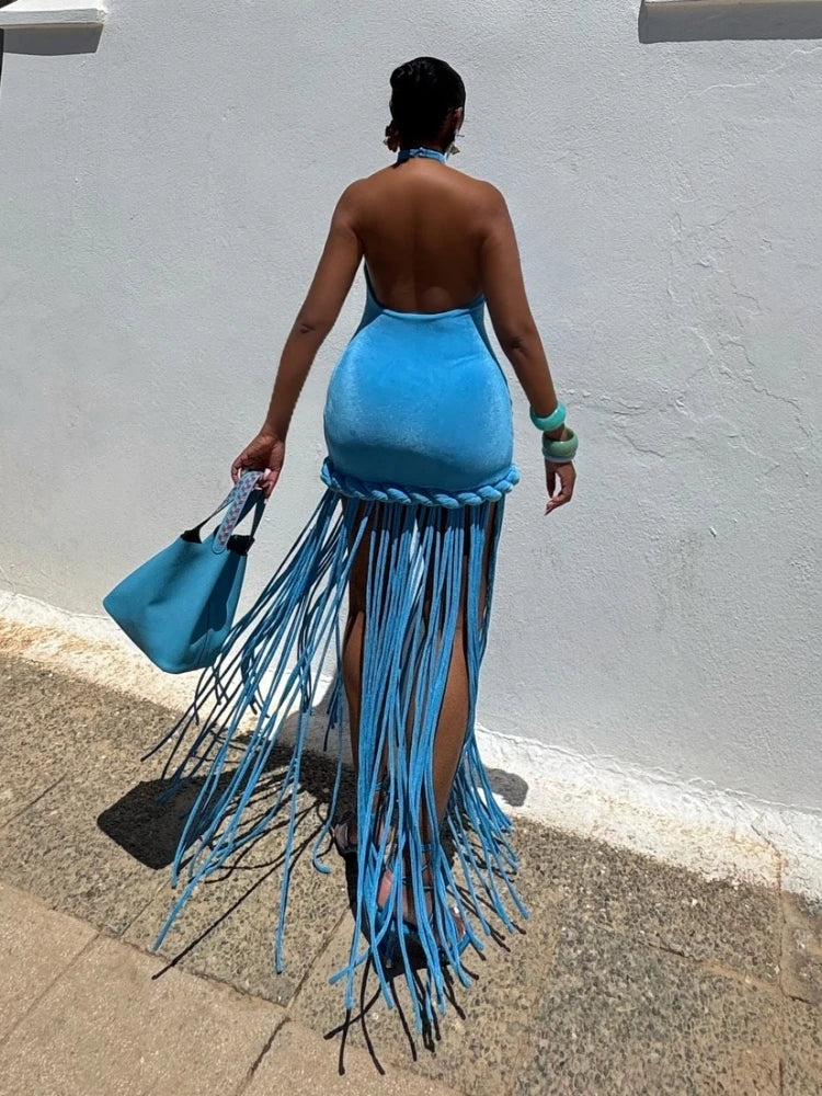Person wearing a blue fringe dress against a gray wall.