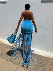 Person wearing a blue fringe dress against a gray wall.