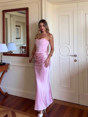 Woman in a pink dress standing in a room with a mirror and door.