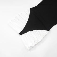 Black swimsuit with ruffled white bottom on a light gray background