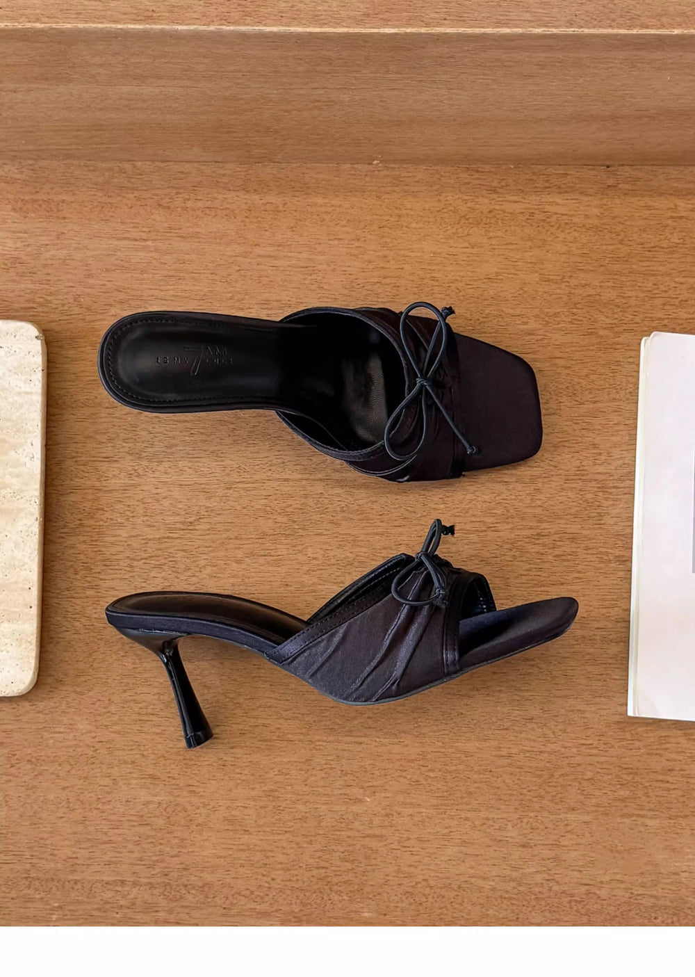 Black high-heeled shoes on a wooden surface