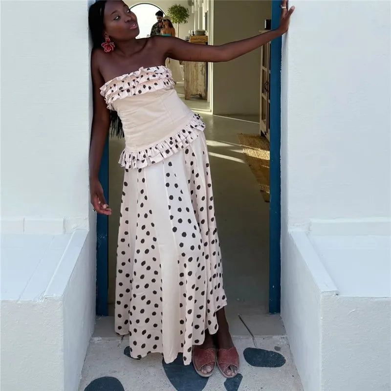 Woman in a strapless polka dot dress standing in a doorway.