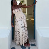 Woman in a strapless polka dot dress standing in a doorway.
