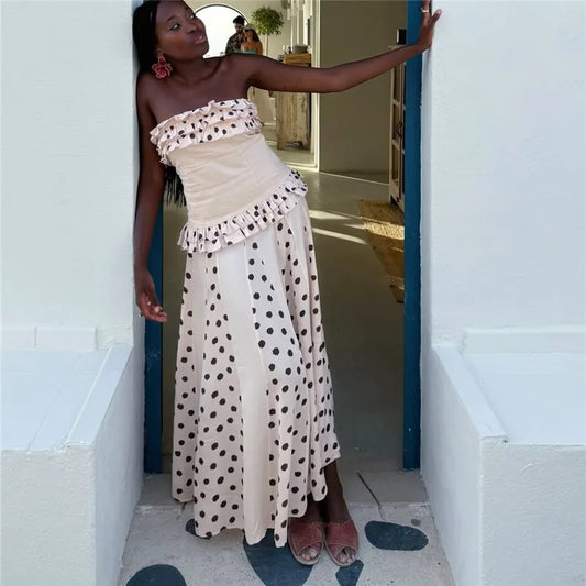 Woman in a strapless polka dot dress standing in a doorway.