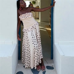 Woman in a strapless polka dot dress standing in a doorway.