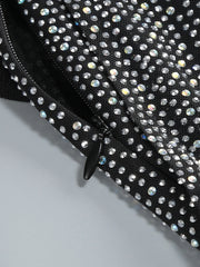 Black clutch bag with rhinestone embellishments on a light gray background