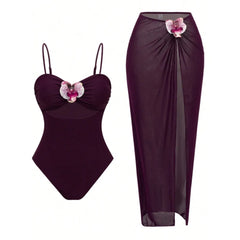 Wine red one-piece swimsuit with adjustable straps and cutout, paired with a high-slit sarong skirt featuring floral applique.