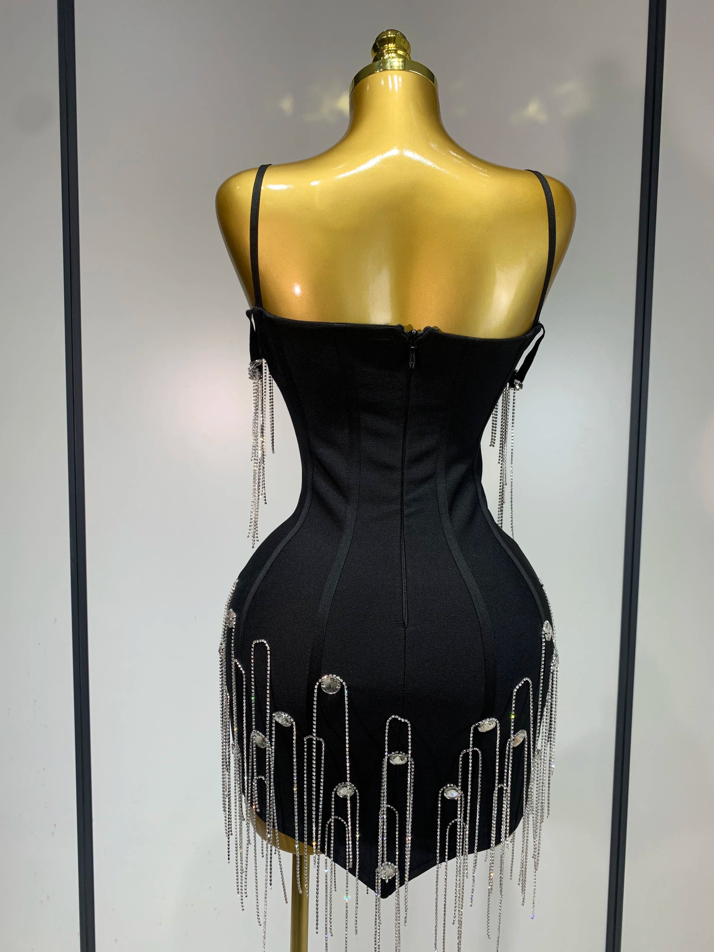 Black dress with silver fringe on a mannequin against a white background