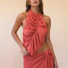 Woman wearing a coral halter neck dress with ruched details on a beige background