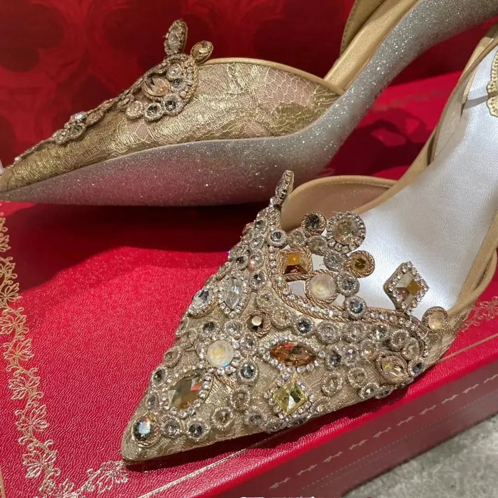 Elegant high-heeled shoes with intricate gemstone detailing on a red fabric background